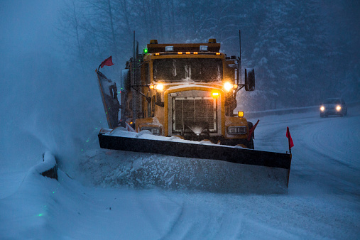 Truck plowing snow off the road at night.