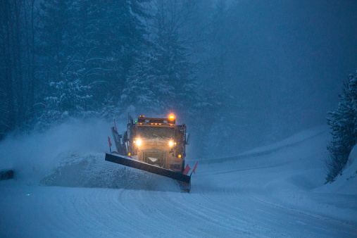 Spindleruv mlyn, Czech Republic - January 27, 2022: Red snowplow. Spruce forest. Snowy winter weather in the mountains at the ski resort.