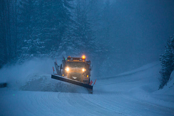 Snowplow plowing the highway during snow storm. Truck plowing snow off the road at night. snow plow stock pictures, royalty-free photos & images