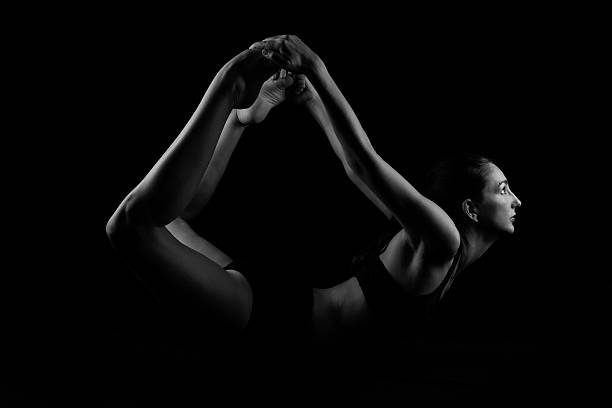istock Young woman doing yoga stretches on black background 536174007
