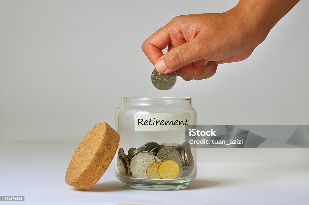 Woman Hand Putting a Coin into Glass Bottle for retirement 2015 Stock Photo