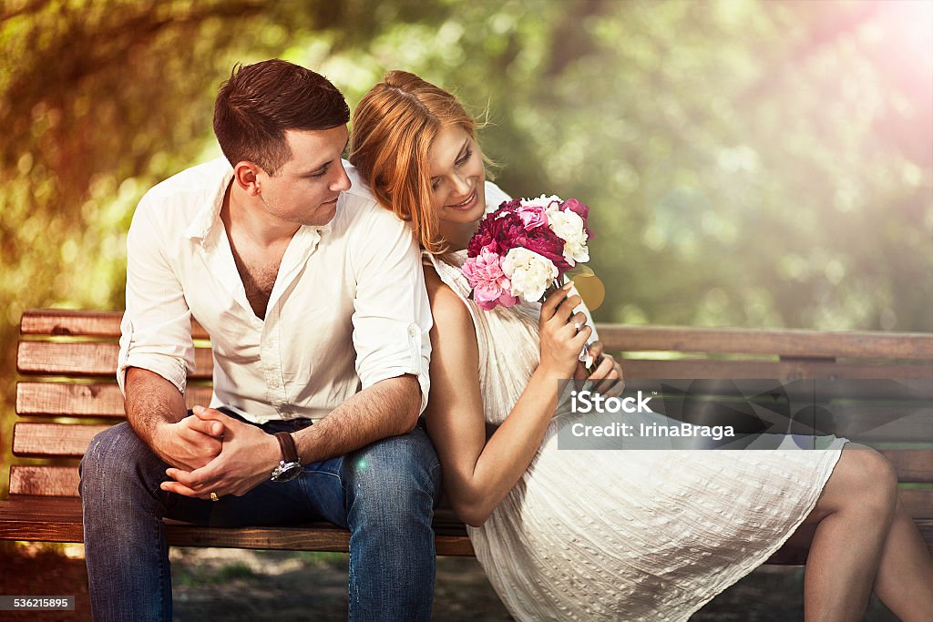 Young beautiful couple in the park.  Man proposing woman Love and celebrate concept. Young beautiful couple sitting in the park and man proposing woman. 2015 Stock Photo