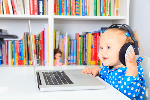 little girl with headphones and laptop, early learning
