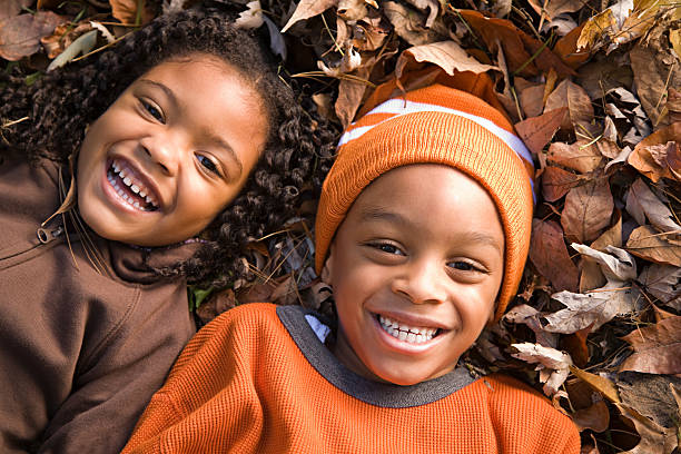 niños acostado de hojas - actividades recreativas fotos fotografías e imágenes de stock