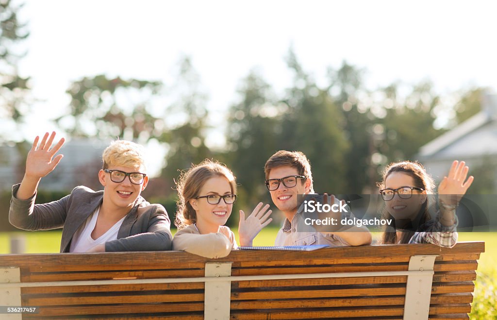 group of students or teenagers waving hands summer holidays, education, campus and teenage concept - group of students or teenagers in eyeglasses waving hands Campus Stock Photo