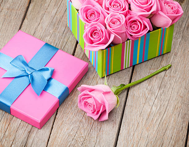 Valentines day gift box full of pink roses over wooden table