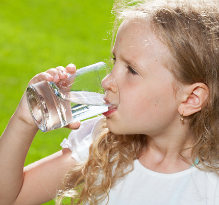 Child drinking water. Girl outdoors