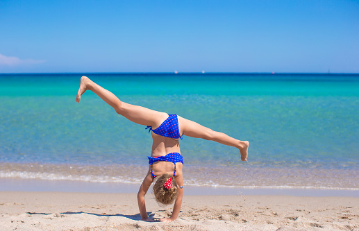 Young Caucasian woman in swimwear dancing on the beach during her vacation