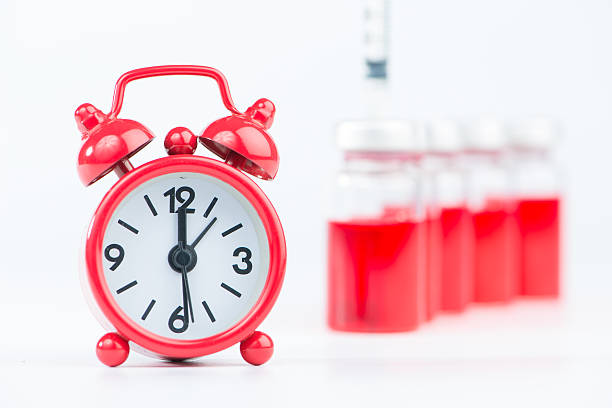 istock Alarm clock on medicine vials and injection syringe background 536244781