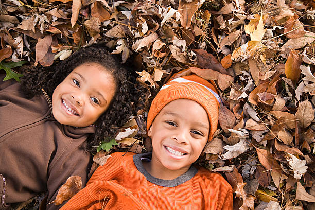 Kids lying on leaves stock photo
