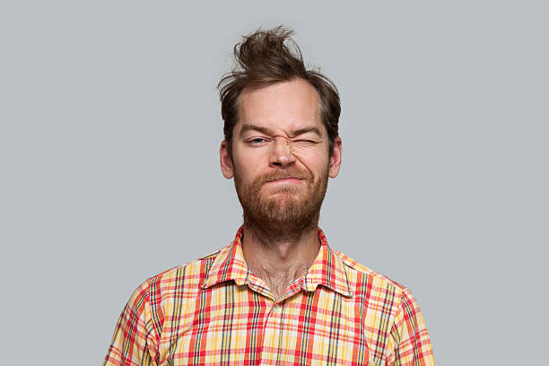 Grimacing Man Attractive man squints one eye, isolated on gray making a face stock pictures, royalty-free photos & images