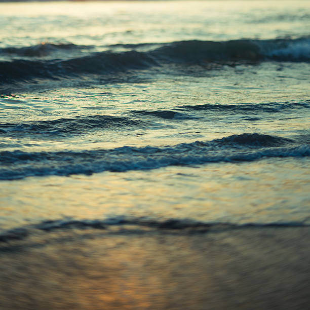Sea waves in motion at sunset captured with long exposure, abstract shoreline water movement.