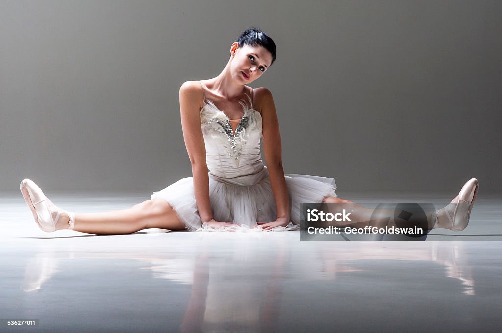 Young attractive ballerina sitting on floor stretching out legs Young attractive ballerina sitting on floor stretching out her legs 2015 Stock Photo