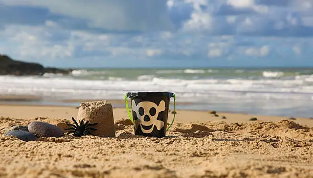 Photo of Spooky black bucket, sand castle and spider on lovely beach