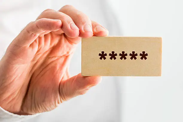 Man holding a wooden block with five stars denoting top or premium rating or quality, close up of his hand.
