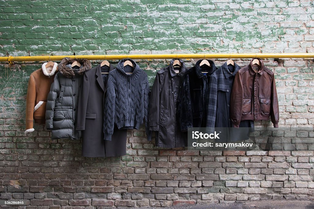 Men&amp;#39;s trendy clothing on hangers Men&amp;#39;s trendy clothing on grunge brick wall. Concept background Clothing Stock Photo