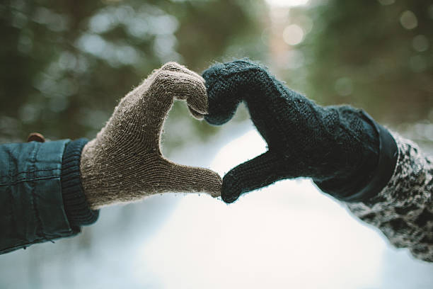 Two hands in gloves holding love heart symbol stock photo