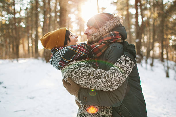 Young hipster couple hugging each other in winter forest stock photo