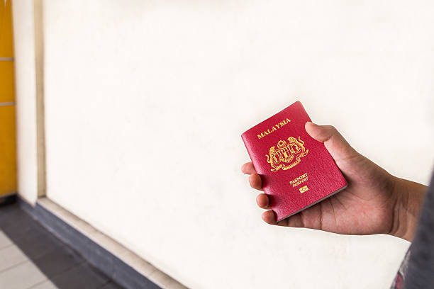 istock Hand holding Malaysia international passport against wall backgr 536291366