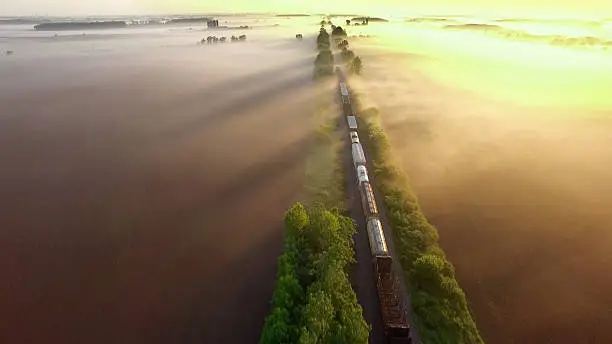 Photo of Freight train rolls across surreal, foggy landscape at sunrise