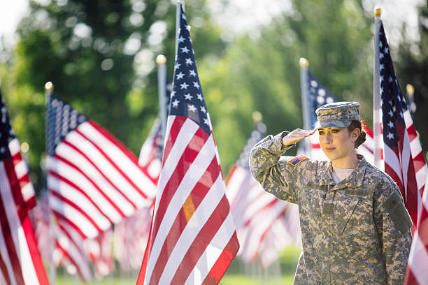 American Female Soldier saluting in front of American Flags stock photo
