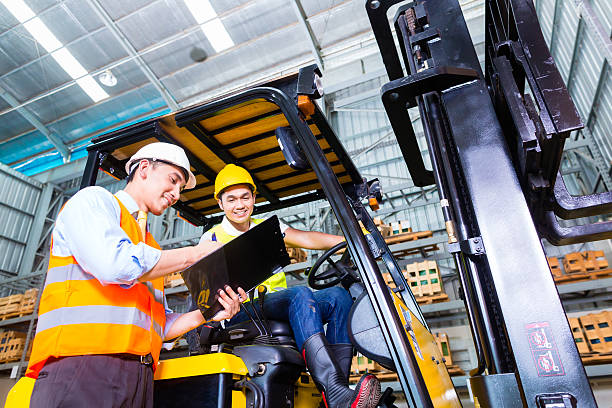 Asian lift truck driver and foreman in storage stock photo