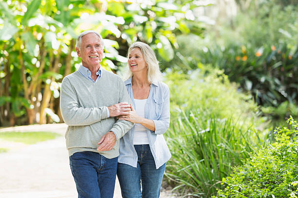 retrato de pareja senior caminando en el parque - couple mature adult action walking fotografías e imágenes de stock