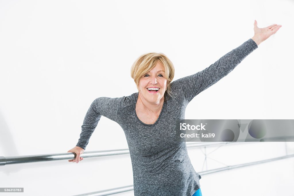 Woman exercising in dance studio Senior woman (60s) doing barre exercises in dance studio. Mature Women Stock Photo