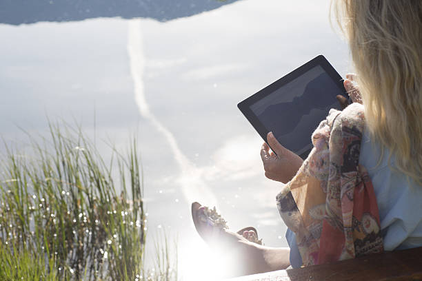 istock Woman uses digital tablet besides mountain lake 536314521