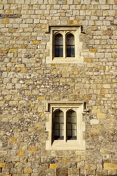 A wooden window with diamond leaded pattern glass on a Tudor stone building.