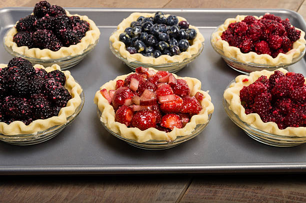Baking homemade fresh fruit pies Homemade fresh fruit pies on a tray made with strawberries raspberries blueberries blackberries marionberry stock pictures, royalty-free photos & images