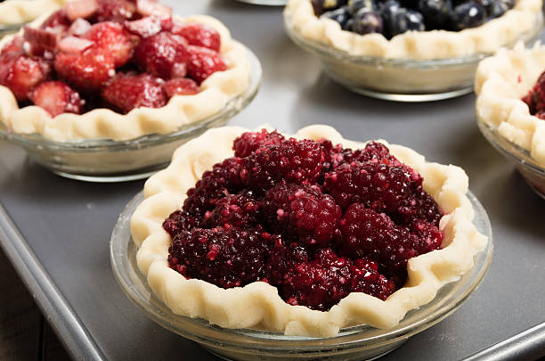Baking homemade fresh fruit pies Homemade fresh fruit pies on a tray made with strawberries raspberries blueberries marionberry stock pictures, royalty-free photos & images