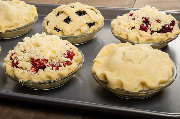 Baking homemade fresh fruit pies Homemade fresh fruit pies on a tray made with strawberries raspberries blueberries blackberries marionberry stock pictures, royalty-free photos & images