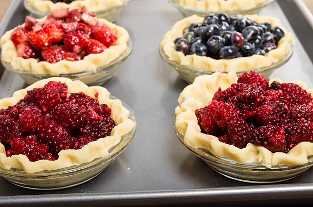 Baking homemade fresh fruit pies Homemade fresh fruit pies on a tray made with strawberries raspberries blueberries marionberry stock pictures, royalty-free photos & images