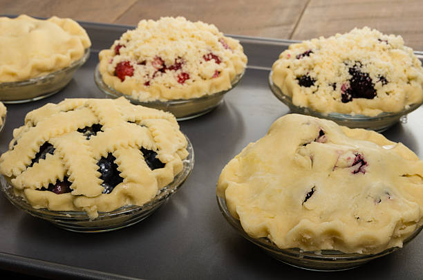 Baking homemade fresh fruit pies Homemade fresh fruit pies on a tray made with strawberries raspberries blueberries blackberries marionberry stock pictures, royalty-free photos & images