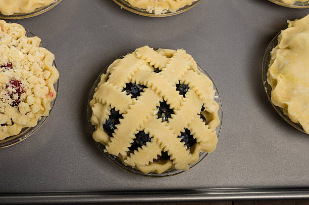Baking homemade fresh fruit pies Homemade fresh fruit pie on a tray made with blueberries marionberry stock pictures, royalty-free photos & images