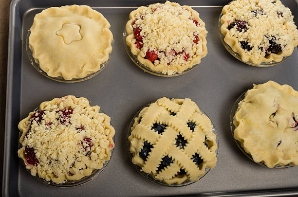 Baking homemade fresh fruit pies Six homemade fresh fruit pies on a tray made with strawberries raspberries blueberries blackberries marionberry stock pictures, royalty-free photos & images