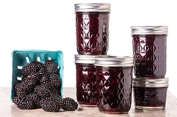 Fresh blackberry jam in jars Fresh homemade blackberry jam in glass jars isolated on white marionberry stock pictures, royalty-free photos & images