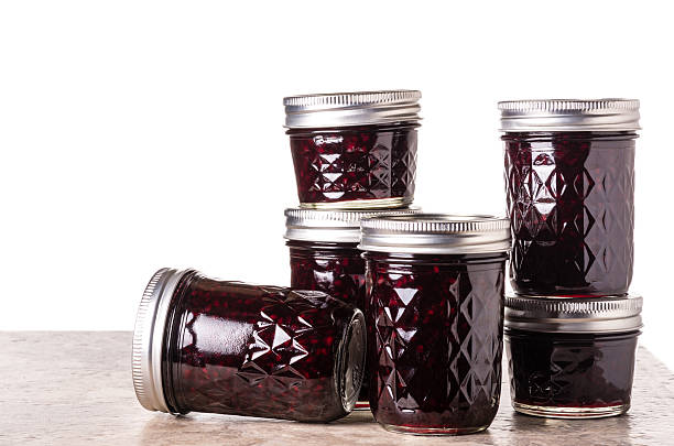 Fresh blackberry jam in jars Fresh homemade blackberry jam in glass jars isolated on white marionberry stock pictures, royalty-free photos & images
