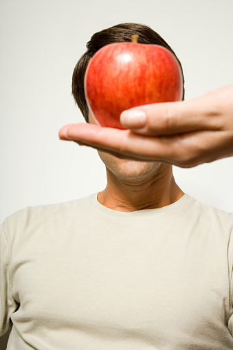 Woman holding apple over man's face