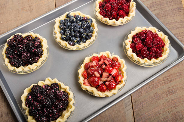 Baking homemade fresh fruit pies Homemade fresh fruit pies on a tray made with strawberries raspberries blueberries blackberries marionberry stock pictures, royalty-free photos & images