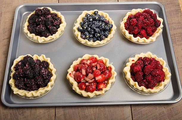 Baking homemade fresh fruit pies Homemade fresh fruit pies on a tray made with strawberries raspberries blueberries blackberries marionberry stock pictures, royalty-free photos & images