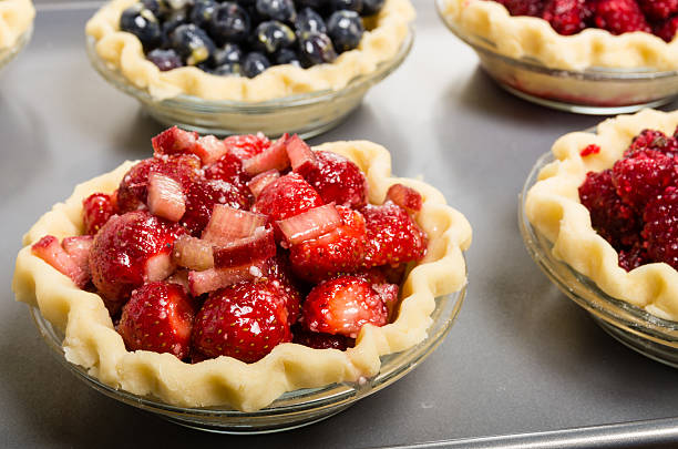 Baking homemade fresh fruit pies Homemade fresh fruit pies on a tray made with strawberries raspberries blueberries marionberry stock pictures, royalty-free photos & images