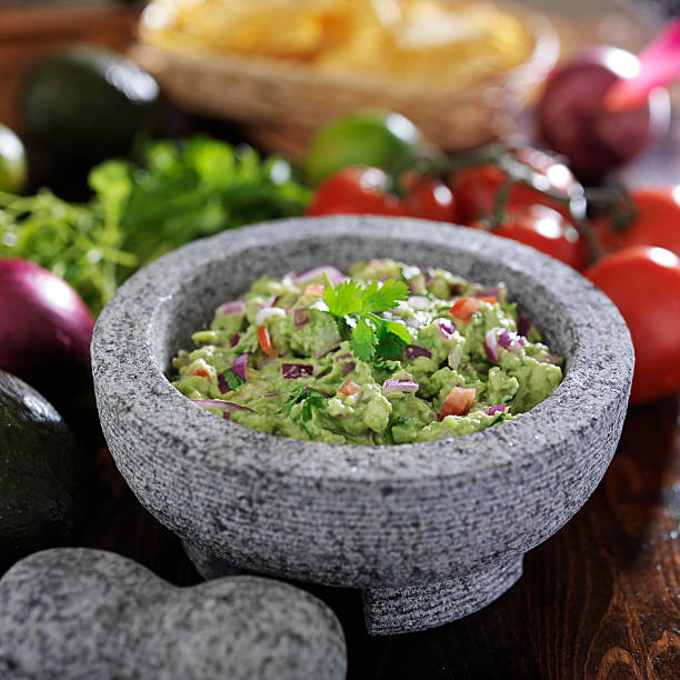 gaucamole in traditional mexican stone molcajete gaucamole in traditional mexican stone molcajete, shot with selective focus fresh cilantro stock pictures, royalty-free photos & images