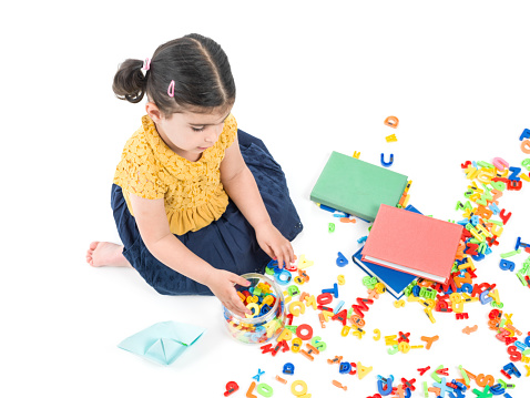 Little girl playing with toy letters and writing on notepad