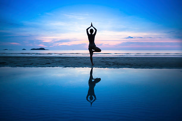 istock Silhouette young woman practicing yoga on beach at surrealistic sunset. 536354403