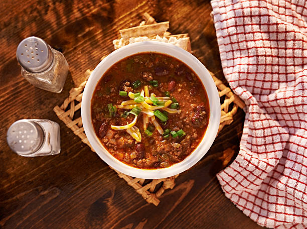 overhead photo of a bowl of chili overhead photo of a bowl of chili with cheese and green onions chili con carne stock pictures, royalty-free photos & images