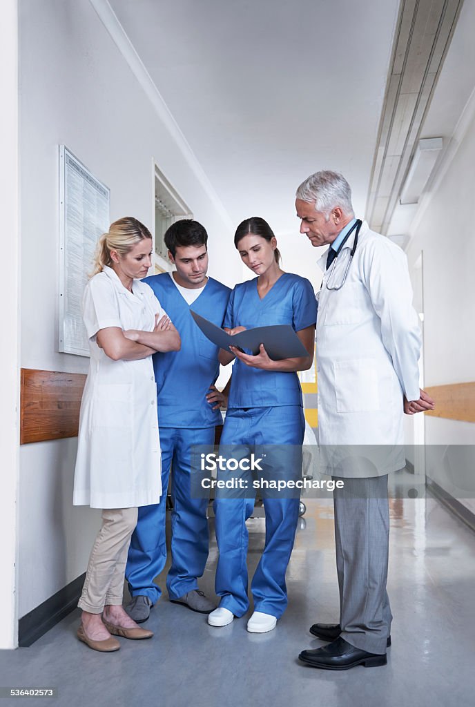 Putting their heads together Full length shot of a medical team discussing a patient file in a hospital corridor Female Nurse Stock Photo