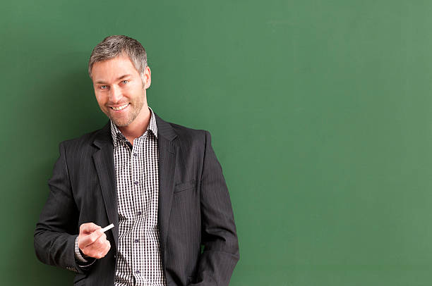 istock smiling teacher with grey hair at blackboard 536403233