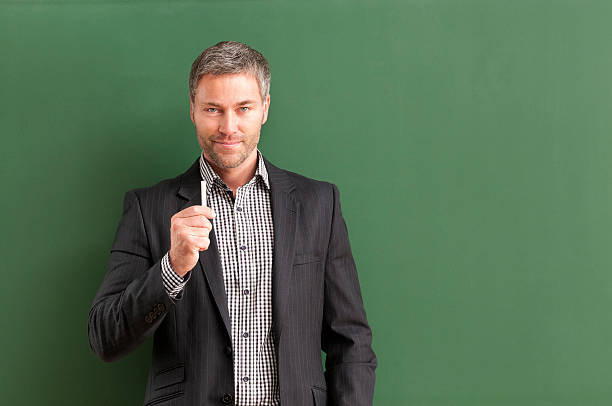 istock smiling teacher with grey hair at blackboard 536403235